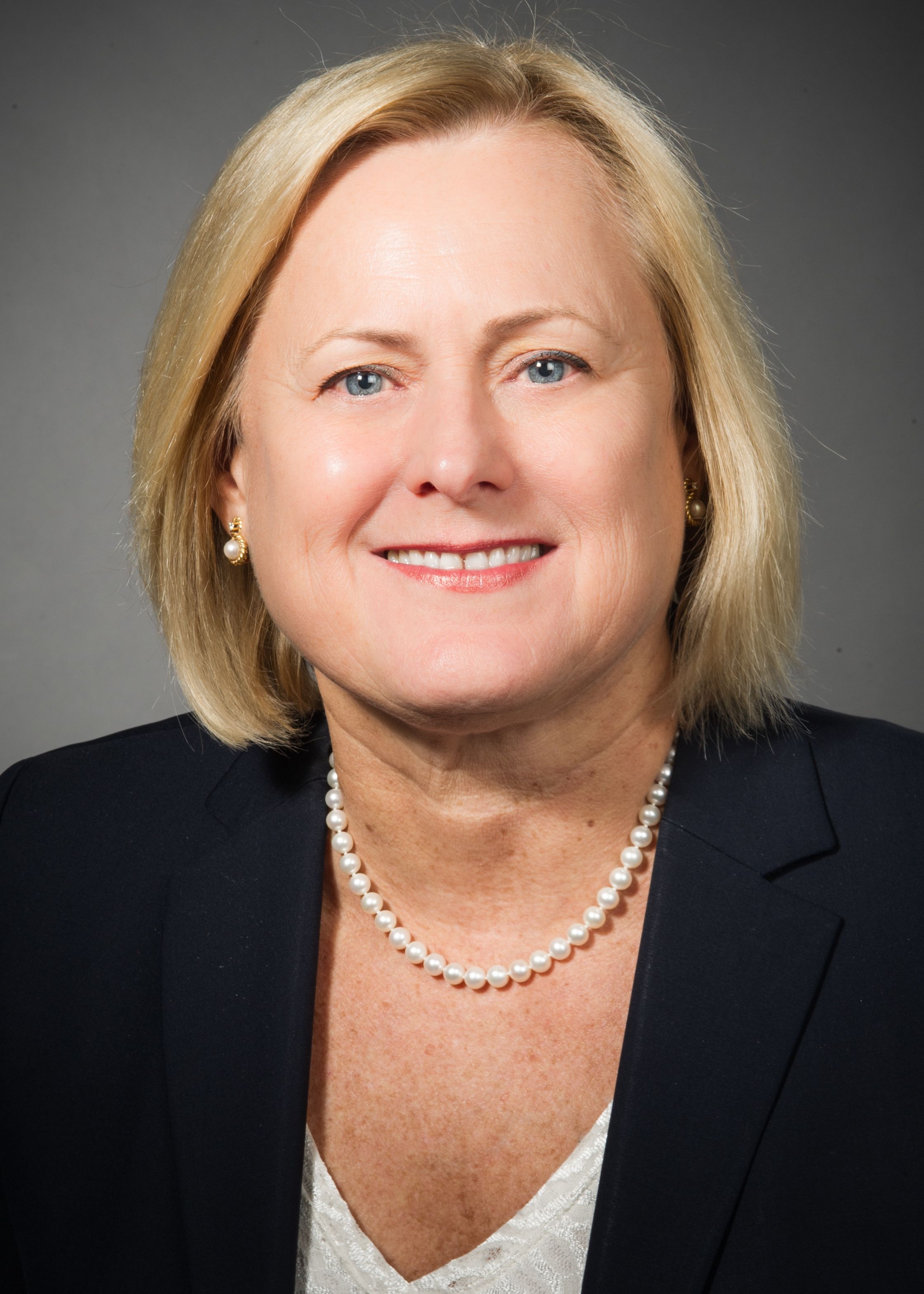 Doreen O'Grady, RN, wearing a dark suit, white blouse and pearl necklace